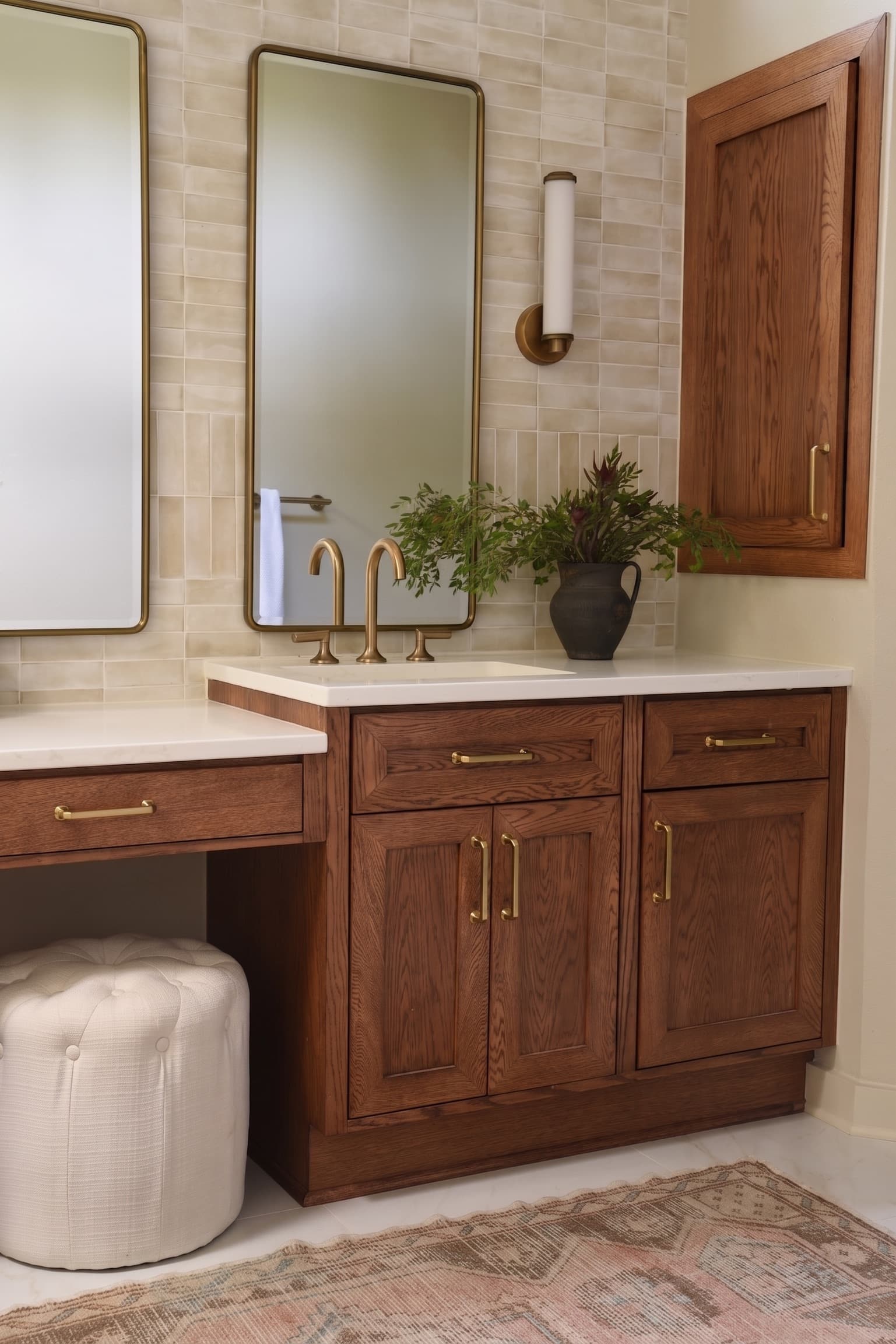 A double vanity in stained oak with brass fixtures, twin thin-framed mirrors and handmade cream wall tile.